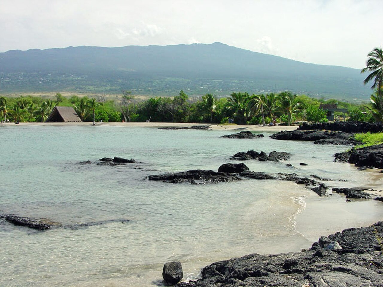 The dormant volcano Hualālai as seen from Kaloko-Honokōhau National Historical Park, on the Big island of Hawaiʻi. 
The ancient settlement of Honokōhau in foreground.
Note "vog" condition from activit