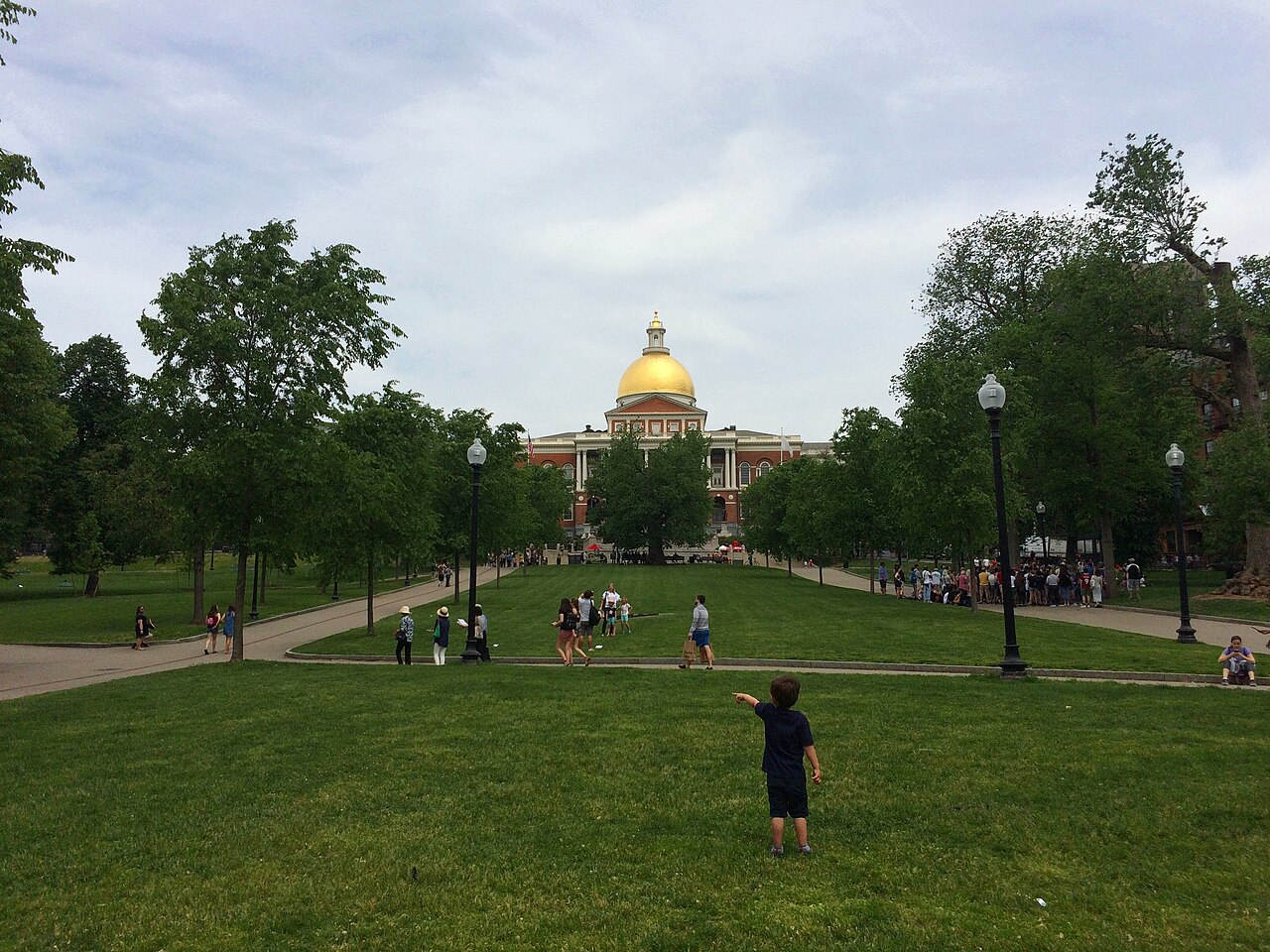 A young child on Boston Common points the way toward the Massachusetts State House.