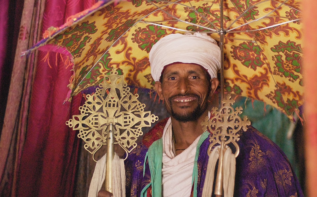 A cleric of the Ethiopian Orthodox Tewahedo Church displays processional crosses under a ceremonial umbrella in the 13th-century rock-hewn church of Bet Abba Libanos in Lalibela, Ethiopia.
While the c