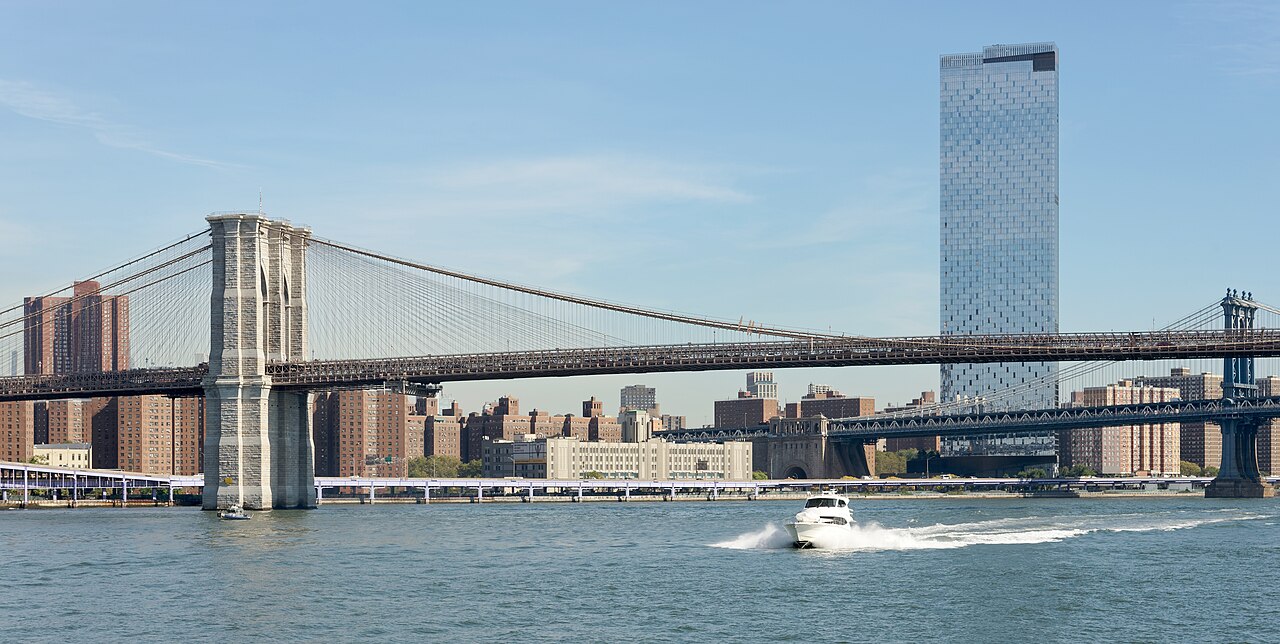 View of Brooklyn Bridge from New York Ferry on East River. Manhattan Bridge and One Manhattan Square skyscraper in the background