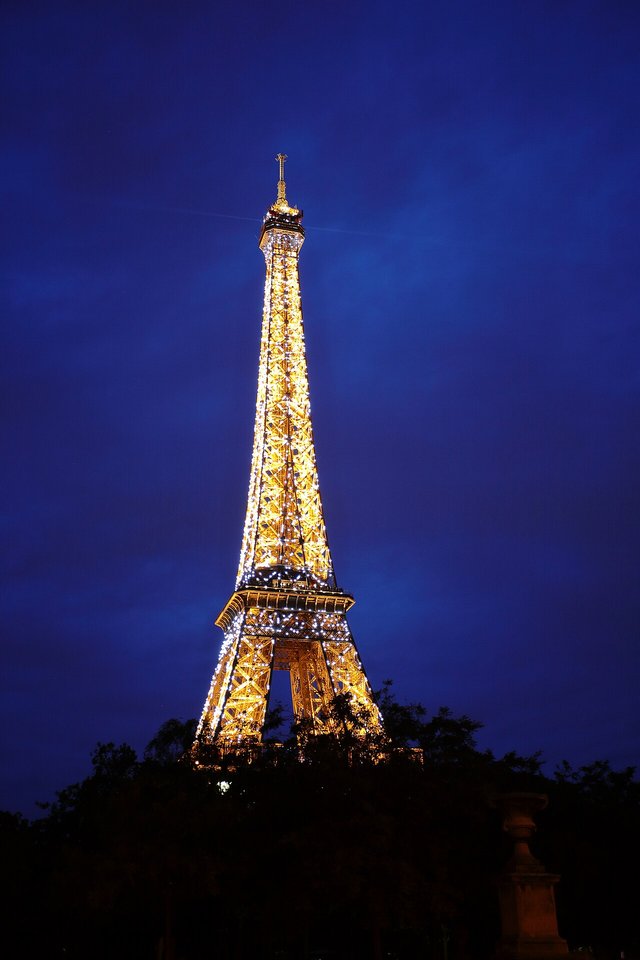 The iconic landmark, illuminated against the deep night sky, embodies the romance and timeless charm of Paris. As the lights twinkle, they reflect the city's enduring allure, making this moment a capt