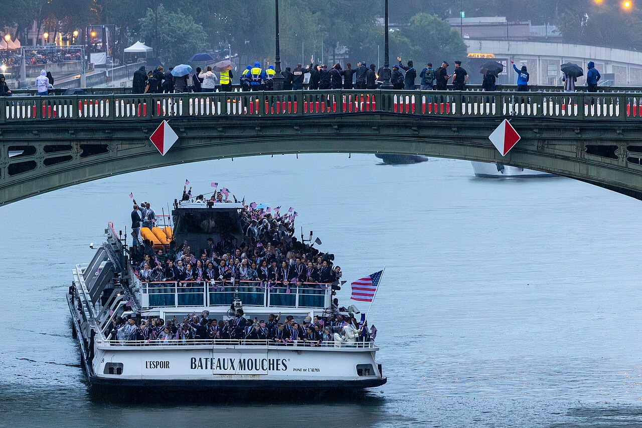 The U.S. Olympic Team waves to onlookers during the opening ceremonies July 26 as its boat cruises along the River Seine.