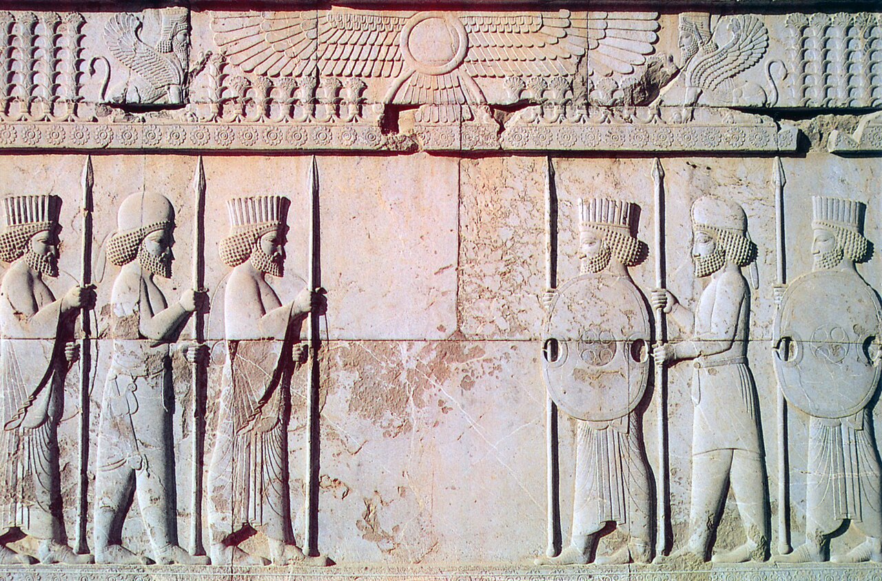Carving of Persian (rounded hats) and Median Soldiers in traditional costume with Farvahar on Persepolis