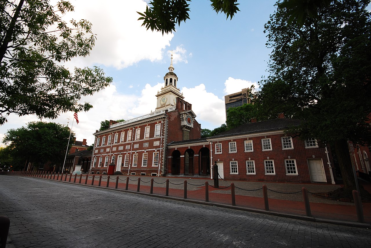 Exterior view of a two story red brick building with center bell tower with an arcade adjoining it to a smaller red brick building.
Look for the reconstructed Stretch clock on the west wall of Indepen