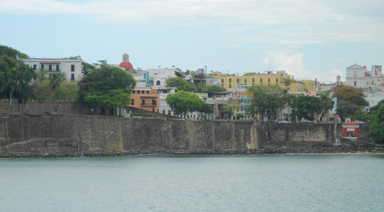 A mini-panorama of the scene as the cruise ship enters San Juan harbor.  Casa Blanca is at the left.  The old city gate is at the far right, and San Juan Cathedral is at the upper right.  
The city wa