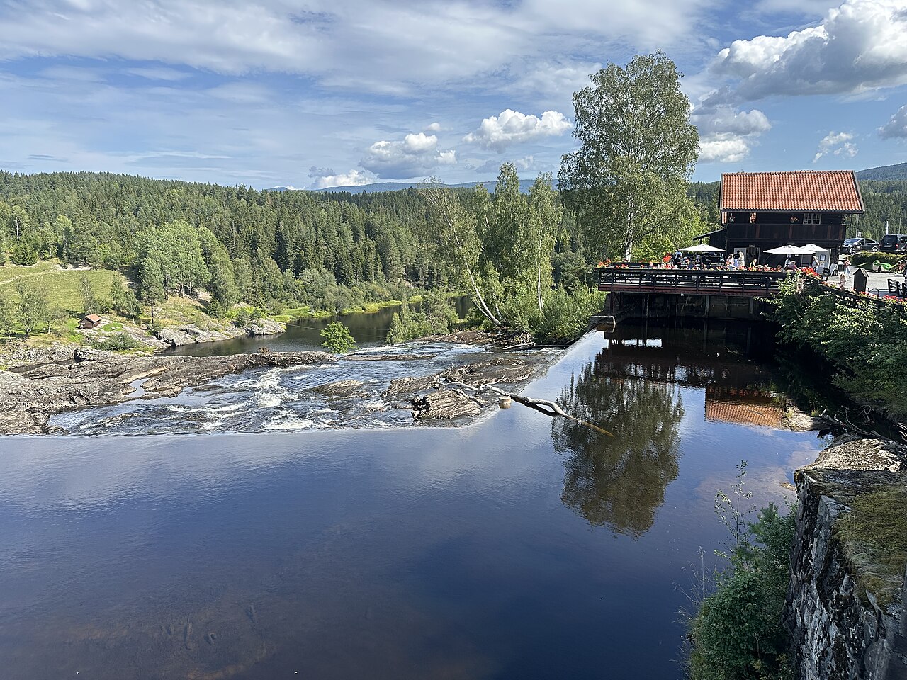 Buildings by the Haugfossen (Haugfoss) waterfall in Modum municipality, Norway.  A reconstructed wooden and stone bridge from c.1837 crosses the river Simoa just before the waterfall. The photo shows 