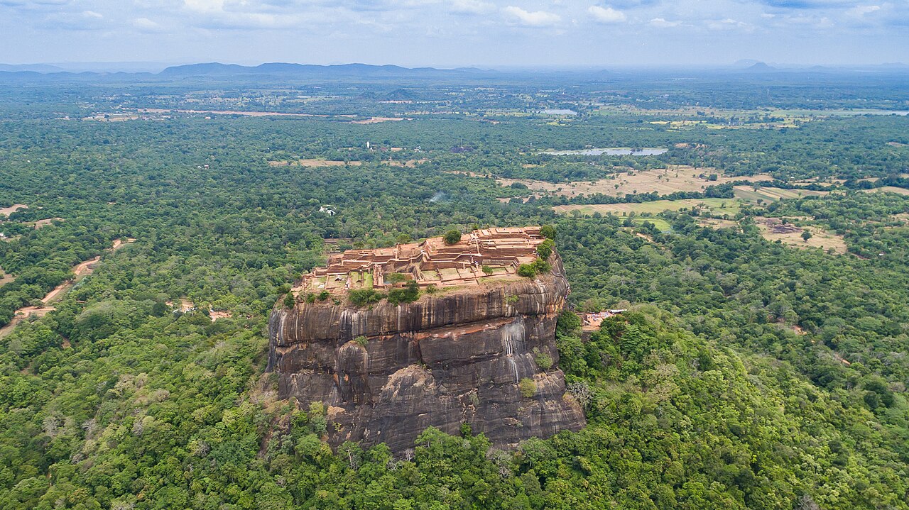 Aerial drone photograph of Sigiriya Lion Rock rising dramatically from the surrounding jungle and plains of central Sri Lanka.