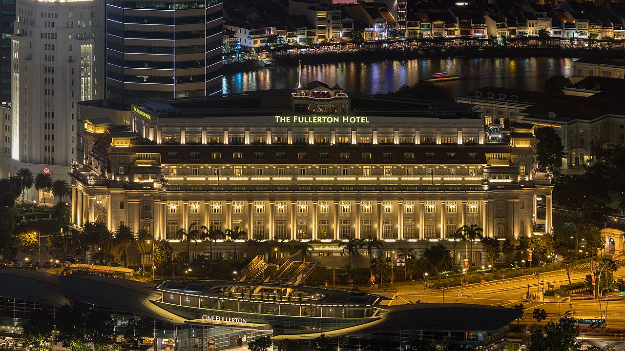 Photographs of The Fullerton Hotel of Singapore at night with colorful lights reflecting in the water (view from the Marina Bay Sands observation deck)