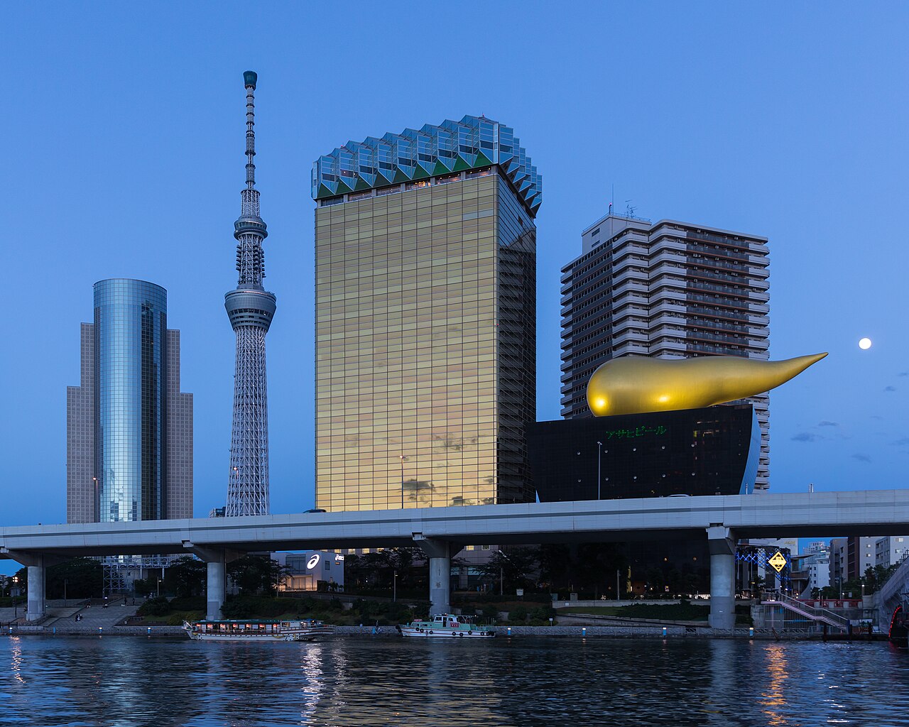 Asahi Breweries headquarters building with the Asahi Flame (also called Super Dry Hall, or Flamme d'Or) designed by Philippe Starck on the Asahi Beer Hall, and Tokyo Skytree, as seen from the wharf at